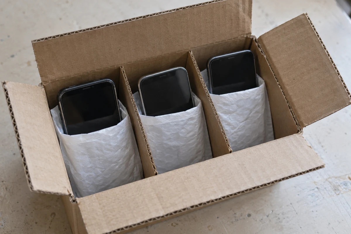 Used handsets in separate padded sleeves and cardboard dividers in an open box.